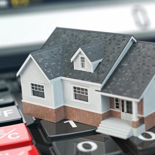 Das Modell eines Hauses steht auf einem Taschenrechner | Immobilie bewerten