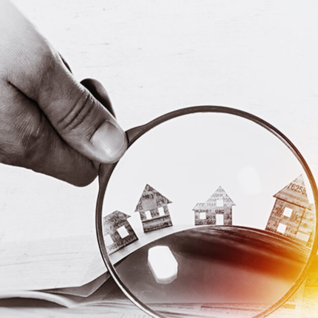 Paper house under a magnifying lens; Immobilienkauf