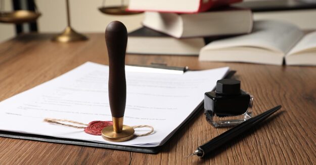 Notarielle Urkunde mit Siegelstempel, Tintenfass und Feder auf einem Holztisch – Symbolbild für Testament, Erbschaft oder rechtliche Beglaubigung | Notartermin