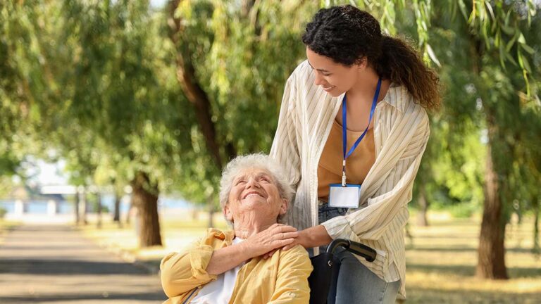 25_08_KW34_Depositphotos_751504074_XL_klein_Copyright_serezniy Eine Seniorin in ihrem Rollstuhl und ihre Pflegerin