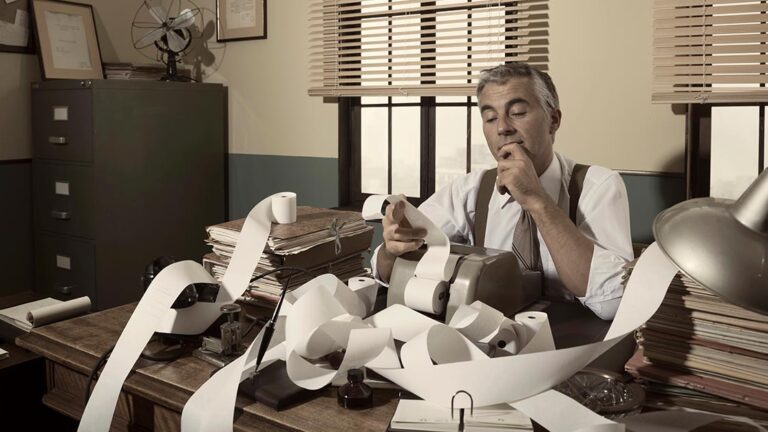 Immobilienverkauf Spekulationssteuer Buchhalter im Büro mit endloser Papierrolle und Rechenmaschine – Symbol für Bürokratie und Steuern | Spekulationssteuer Immobilienverkauf