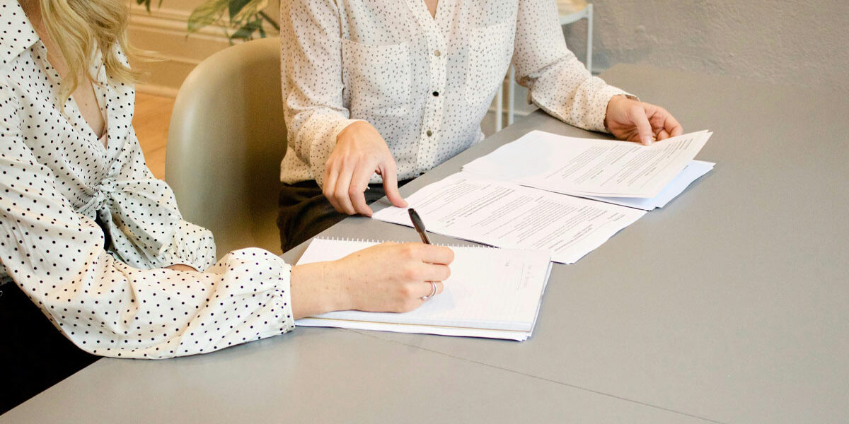 Immobilienverkauf Eine Immobilienkäuferin unterzeichnet den Kaufvertrag bei einer Notarin | Immobilienverkauf