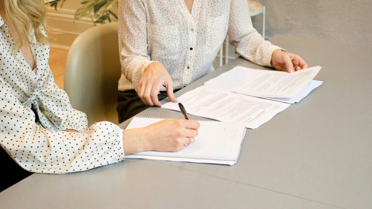 Immobilienverkauf Eine Immobilienkäuferin unterzeichnet den Kaufvertrag bei einer Notarin | Immobilienverkauf