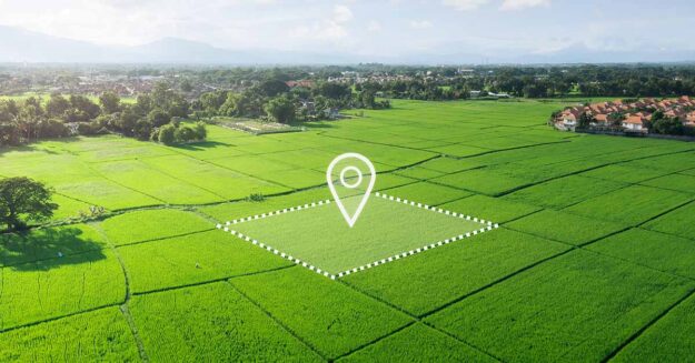 Luftaufnahme eines unbebauten, grünen Grundstücks mit markierter Fläche und Standort-Symbol, das die Entwicklungsmöglichkeiten und den gezielten Verkauf von Bauland veranschaulicht. | Grundstücksverkauf