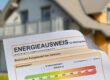 Ansicht eines Energieausweises, im Hintergrund ein Einfamilienhaus | Energieausweis