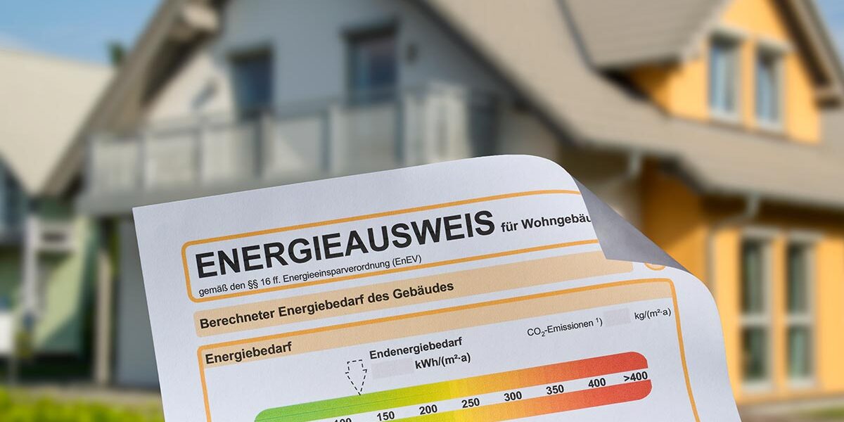 Energieausweis Ansicht eines Energieausweises, im Hintergrund ein Einfamilienhaus | Energieausweis